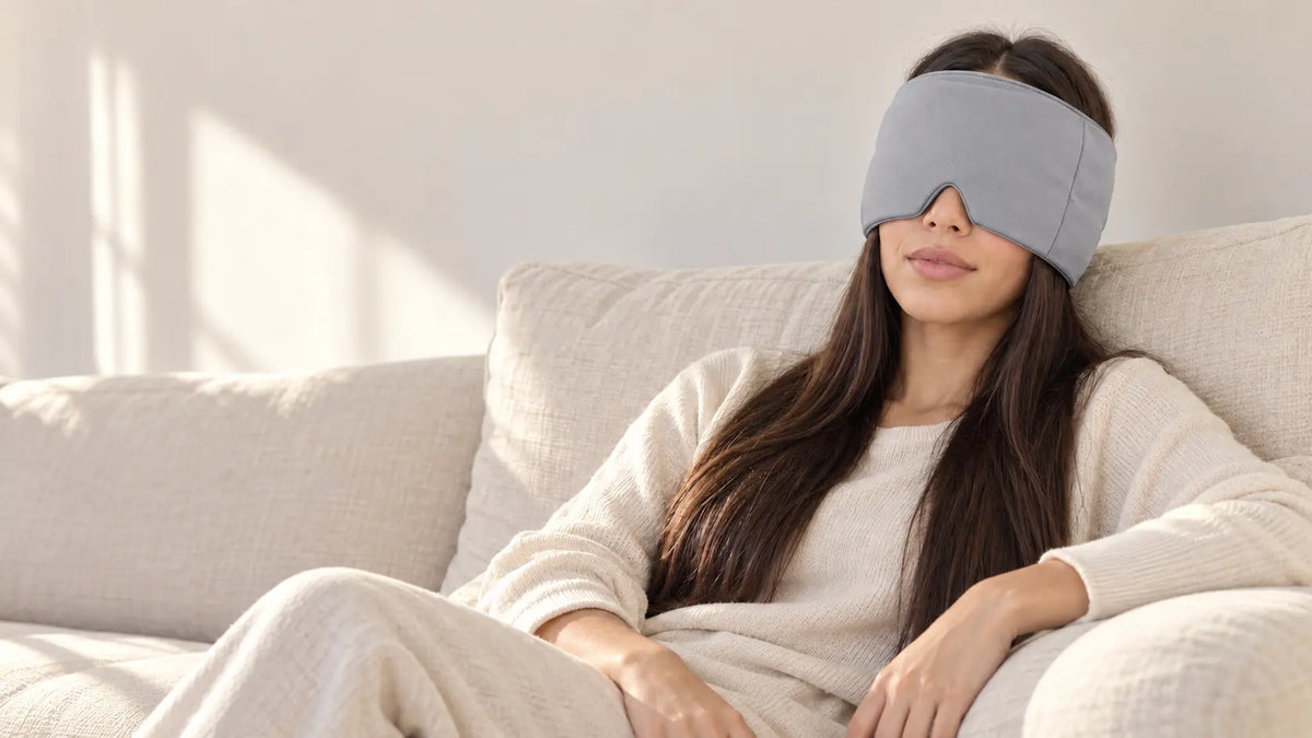 Cryovelle Therapy Mask — Storm Grey, worn by a woman relaxing on a sofa